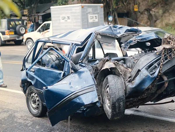 Vehículo azul con el frente aplastado, el techo hundido y una puerta delantera abierta y deformada tras un accidente muy grave en carretera.