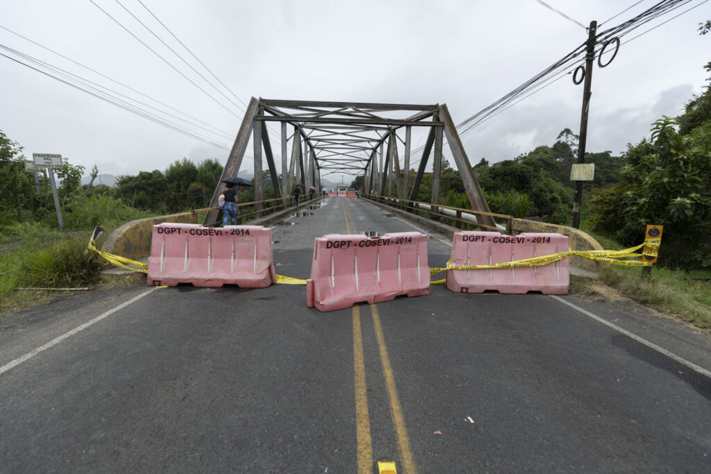 Puente metálico en Costa Rica con el paso vehicular cerrado mediante barreras plásticas y cinta amarilla de precaución.